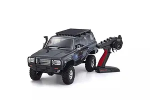 A blue Kyosho Toyota Land Cruiser 60 Series RC rock crawler with a black roof rack and its matching pistol-grip radio transmitter on a white background.