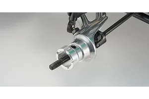 Close-up of a Kyosho RC buggy front wheel hub assembly with a metal steering knuckle and wheel hex adapter on a plain background.