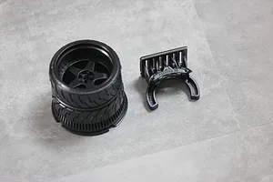Black Pandora RC steering wheel accessory for Sanwa transmitters, featuring a detailed wheel rim and a separate mounting bracket on a grey surface.