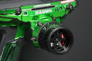 A black 6-spoke RC transmitter steering wheel accessory by Pandora RC installed on a green metallic Sanwa radio controller.