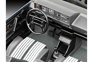A detailed interior view of a 1/24 scale model car showing the dashboard, steering wheel, and striped seats.