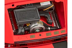 Close-up of the detailed engine bay of a 1/24 scale Revell Porsche 911 Turbo model kit, showing the engine block, intercooler, and various warning decals.
