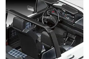 Close-up of the detailed interior of a 1/24 scale model VW Golf 1, showing the dashboard, steering wheel, seats with plaid fabric, and roll bar.