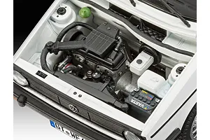 Close-up of the detailed engine bay of a 1/24 scale Revell 1974 VW Golf 1 model kit, showing the engine block, battery, and white body panels.