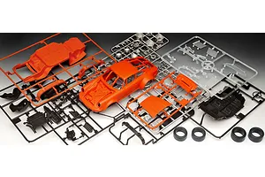 Plastic model kit parts for a Revell Porsche 934 RSR, including orange car body, black chassis, and clear windows on sprues.