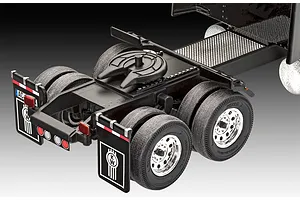Close-up of the rear chassis and dual wheels of a Kenworth model truck, showing the fifth wheel hitch and mudflaps with the KW logo.