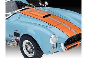 Close-up of a light blue and orange Shelby Cobra 427 model car with racing decals, showing the hood scoop, front wheel, and headlight.