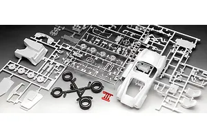 Unassembled plastic model kit parts for a 1/24 scale Shelby Cobra 427, including white body shell, chrome-plated parts, black tires, and red clear parts.