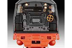 Close-up view of the detailed cab interior of a 1/87 scale model steam locomotive, featuring black controls and gold-painted wheels against a red base.