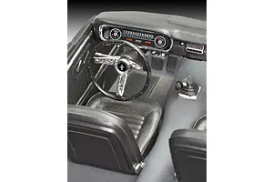 Close-up of the detailed interior of a 1/24 scale 1965 Ford Mustang model car, showing the dashboard, steering wheel, and front bucket seats.