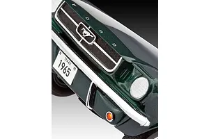 Close-up of the front grille and bumper of a dark green 1965 Ford Mustang model car, showing the Mustang emblem and Texas license plate.