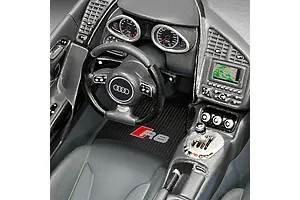 Close-up of the detailed interior of a 1/24 scale Revell Audi R8 plastic model car, showing the dashboard, steering wheel, and R8 branded floor mat.