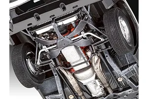 Underside view of a 1/25 scale plastic model 1970 Dodge Charger showing the chassis, engine block, transmission, and front suspension details.