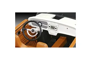 Close-up of the interior of a 1/32 scale VW Beetle model kit, showing the white dashboard, black steering wheel, and tan seats.