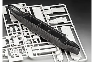 A black plastic ship hull piece resting on top of white plastic model kit sprues for a 1/1200 scale Titanic model.