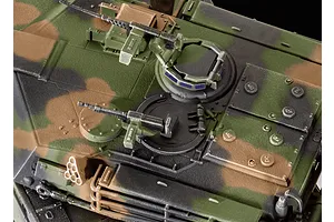 Top-down view of a 1/72 scale plastic model M1 Abrams tank turret featuring detailed camouflage paint, hatches, and mounted machine guns.