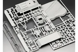 Unassembled grey plastic model kit parts for a T-34-76 tank on sprues, including hull, turret, tracks, and a small terrain base.