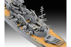 A high-angle close-up of a 1/1200 scale plastic model battleship, showing the grey superstructure, tan deck, and gun turrets.