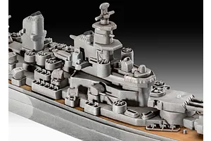 Close-up of a grey plastic model battleship deck showing the superstructure, turrets, and radar tower details.