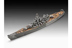 A high-angle studio shot of a 1/1200 scale plastic model of the USS New Jersey battleship, showing the grey hull and tan deck details.