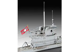 A close-up view of the conning tower of a 1/144 scale Revell U96 submarine model, showing the grey hull, periscopes, railing, and a small flag.