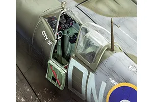 Close-up of a 1/32 scale plastic model Spitfire cockpit with open canopy and detailed interior.