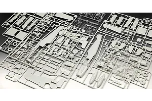 Several grey plastic model kit sprues containing various aircraft parts for a Messerschmitt Bf 109 model, including fuselage and wing sections.