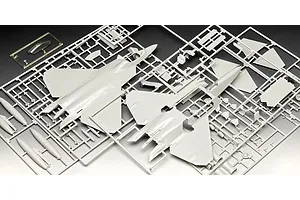 Plastic model kit sprues for a 1/72 scale F-22A Raptor aircraft, showing grey fuselage parts and a clear canopy piece on a dark background.
