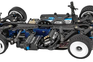 Close-up of the chassis of a Team Associated TC28 1/28 scale RC car, showing the belt drive, Reedy motor, and blue anodized aluminum components.
