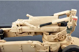 A close-up side view of a 1/16 scale M198 155mm towed howitzer plastic model kit, featuring tan desert camouflage paint and detailed mechanical components.