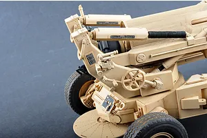 Close-up of a 1/16 scale M198 155mm towed howitzer plastic model kit, showing detailed tan components, wheels, and mechanical controls.