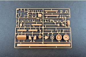 A tan plastic model kit sprue containing various parts for an M198 155mm towed howitzer on a dark grey background.