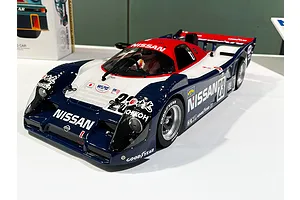 A Tamiya R91CP Group-C RC car model in blue, white, and red Nissan racing livery on a white display surface.