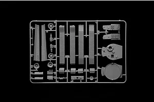 A grey plastic sprue containing various tank model parts, including track segments, turret components, and wheels, set against a black background.