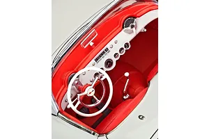 Close-up of the detailed red and white interior of a 1/24 scale 1953 Chevrolet Corvette model car, showing the dashboard, steering wheel, and gear shifter.