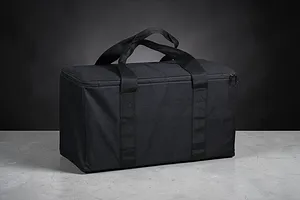 A black rectangular RC storage bag with carry handles, sitting on a grey concrete surface against a dark background.