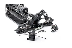 A partially assembled 1/10 scale RC buggy chassis showing the front suspension, differential, and various small screws on a white background.