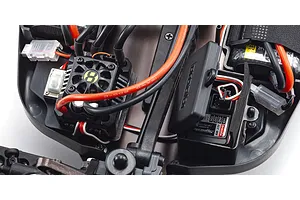 Close-up of the internal electronics of a Kyosho Inferno MP10e RC buggy, showing the ESC with cooling fan and the Kyosho receiver box.
