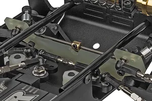 Close-up of the internal chassis components of a Team Associated RC10 buggy, showing steering linkages, suspension parts, and a fiberglass chassis plate.