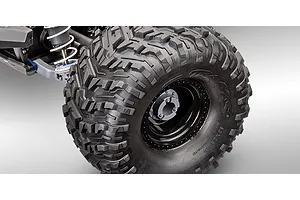 Close-up of a Traxxas RC monster truck wheel and suspension assembly on a grey background.