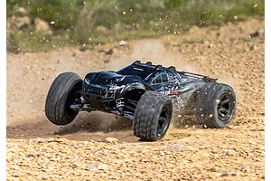 A black Traxxas Rustler 4X4 RC stadium truck driving fast over a dirt track, kicking up dust and gravel.