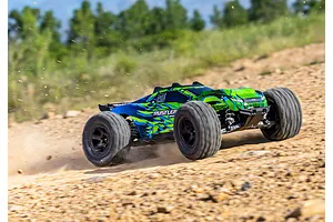 A Traxxas Rustler 4X4 RC stadium truck with a green and blue patterned body driving fast on a dirt track, kicking up dust.