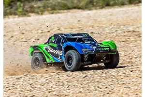 A Traxxas Slash 4X4 RC short course truck driving fast on a dirt track, kicking up dust and gravel.