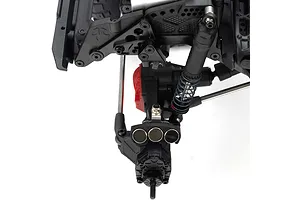 Close-up of an RC crawler front axle assembly featuring three circular metal weight discs mounted on the steering knuckle.
