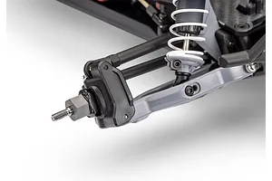 Close-up of the front suspension assembly of a Traxxas RC vehicle, showing the grey A-arm, coil-over shock, and wheel hex hub.