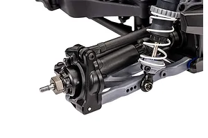 Close-up of the rear suspension and wheel hub assembly of a Traxxas RC monster truck, showing the shock absorber, control arm, and axle nut.