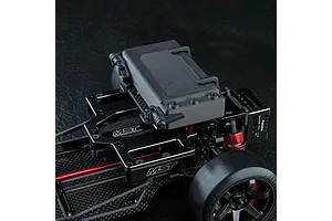 Close-up of an MST RC car chassis featuring a high-mounted battery tray with a black battery pack secured by clips.