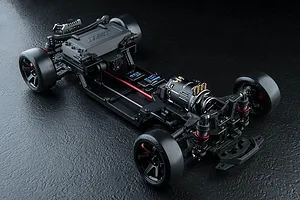 High-angle studio shot of an MST FRX S 1/10 scale RC drift car chassis, showing the front-motor layout and black plastic components on a dark textured surface.
