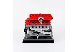 A detailed scale model of a V12 engine with bright red valve covers and silver engine block components, mounted on a black display base.