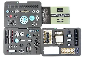 Top-down view of the Teching DM113 four-cylinder engine model kit parts organized in foam trays with an assembly manual.
